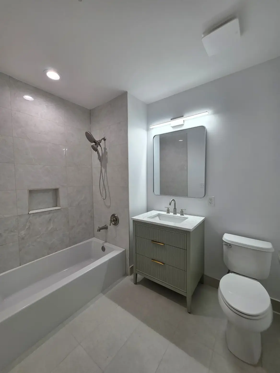 The completed tub bathroom with its sage vanity, new mirror and light bar