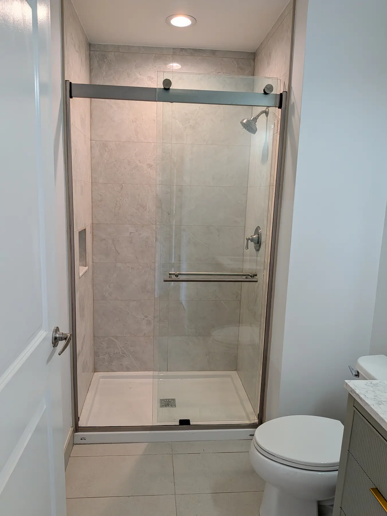 The new walk-in shower with its sliding glass door, niche and large-format tile