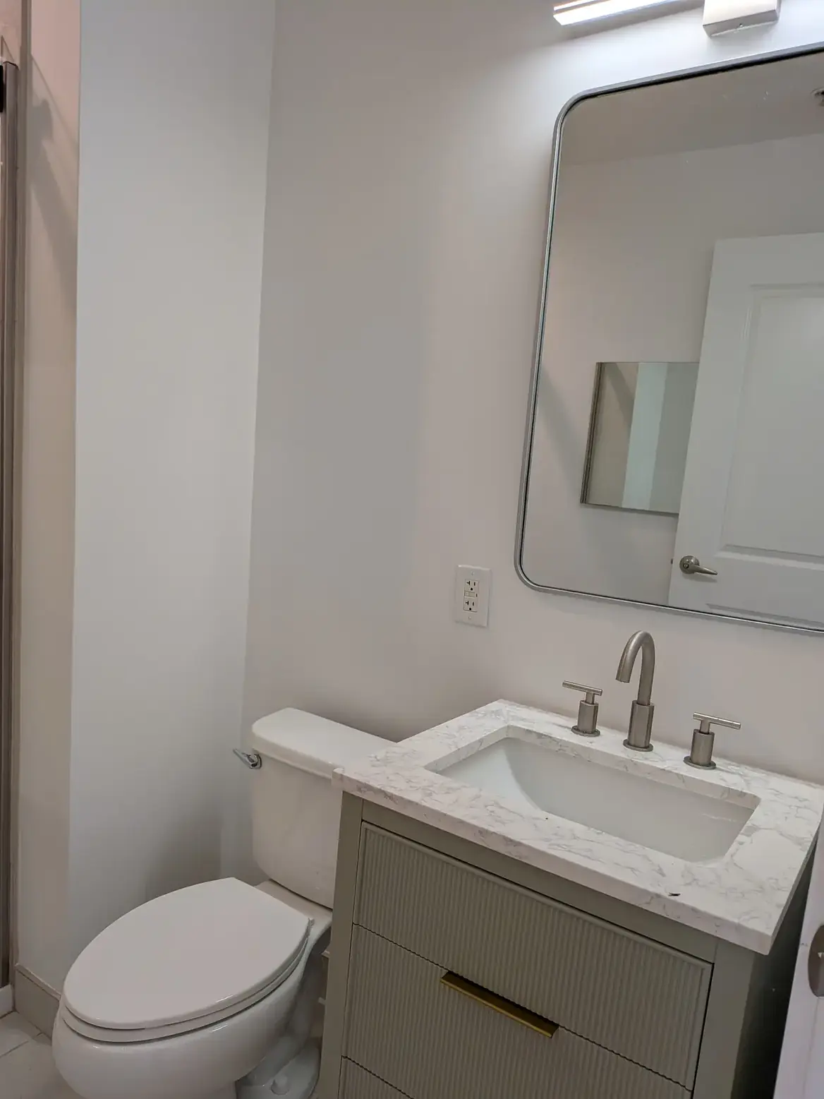 The new vanity with a stone top, brushed-nickel fittings and a round-cornered mirror