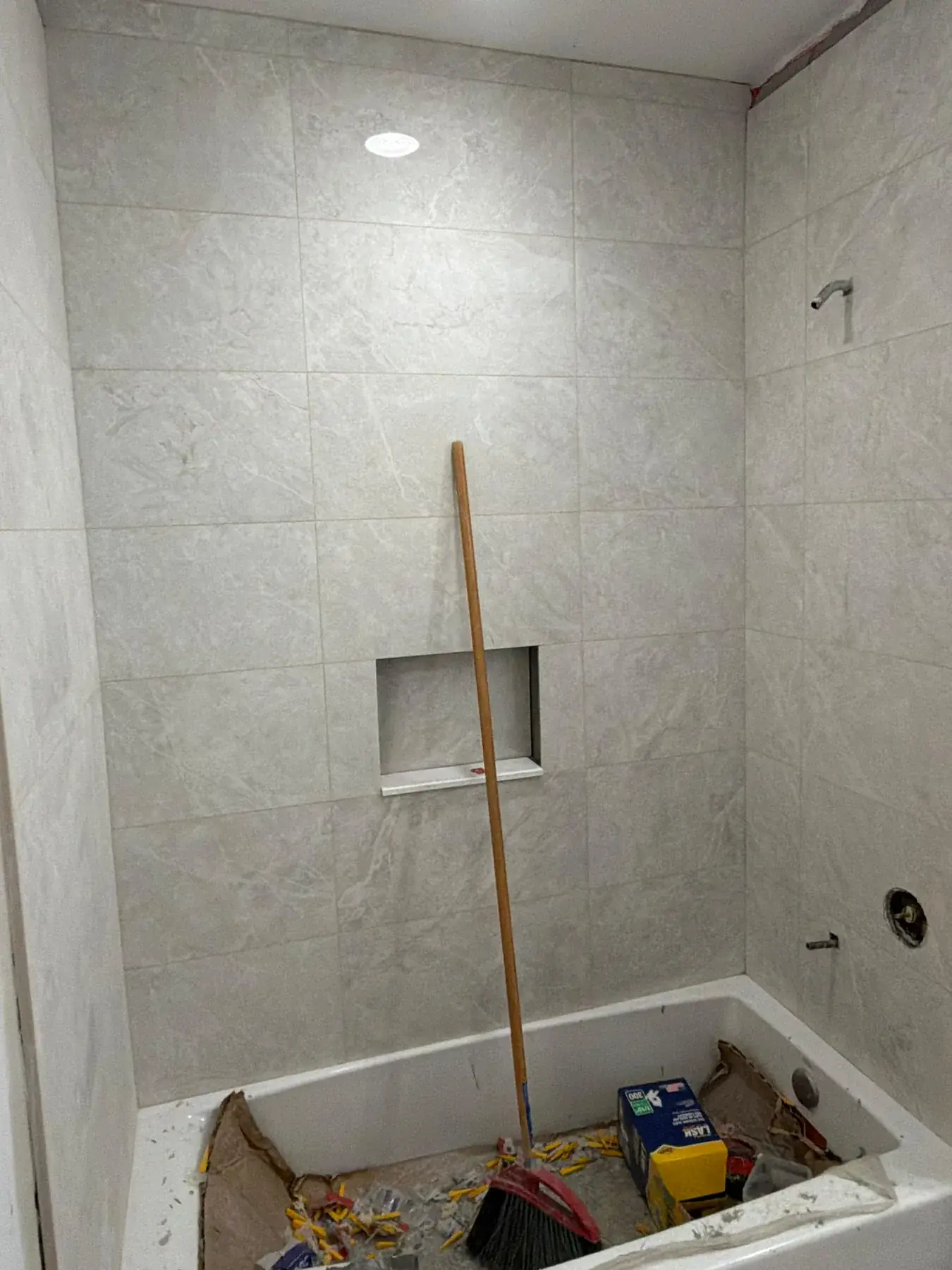 The tiled shower surround, with the tub still protected during work