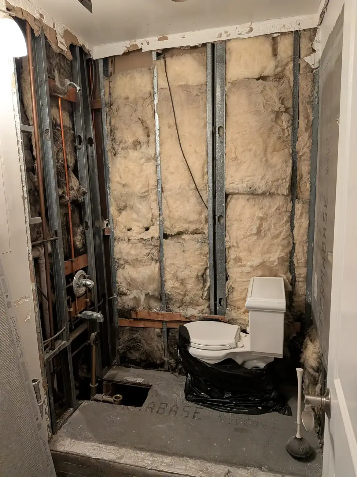 The room stripped back to studs and the original stone wall during demolition
