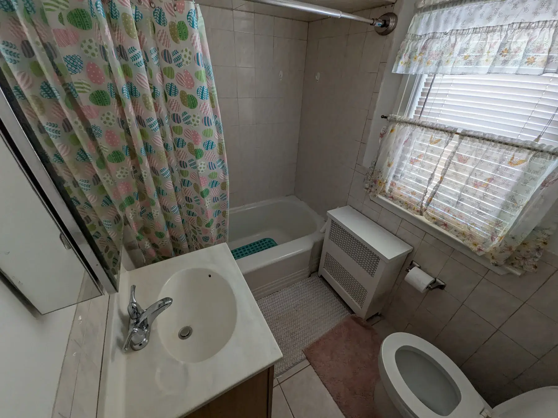 The original bathroom before work began, with a shower curtain and dated wall tile