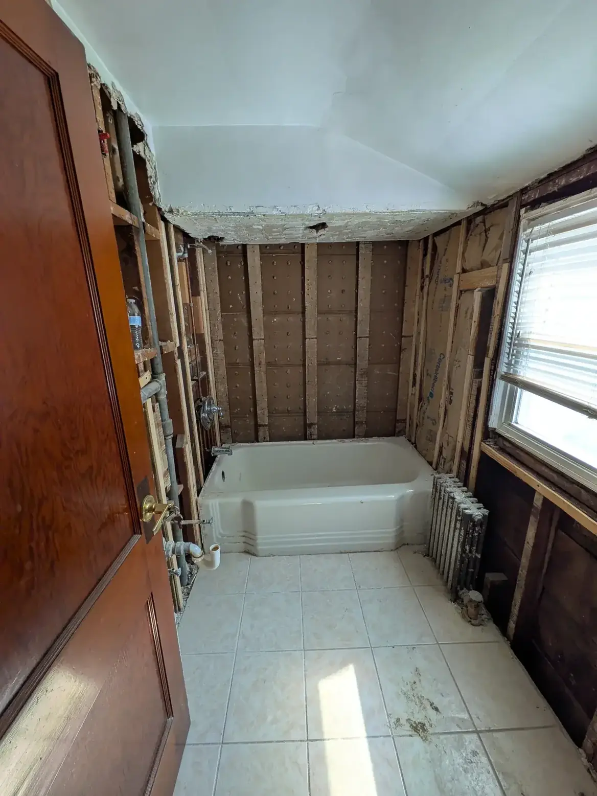 The room stripped back to bare studs with the original tub still in place
